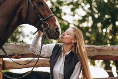 Genç bir dişi binici atının yanında duruyor ve bir yarışa hazırlanıyor. Atlama eğitimini göster. Atları severim..