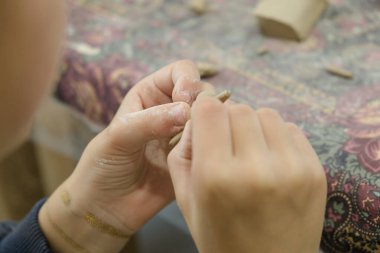 Bir çocuk modellik dersinde bir ürünü kilden şekillendirir..