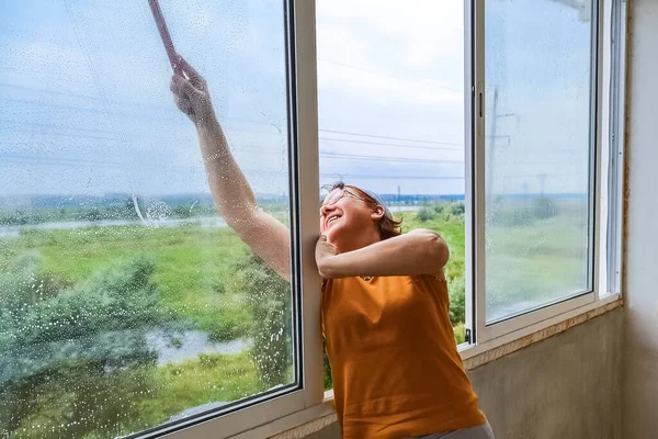 A woman washes the windows on the balcony after repairs. Household chores.
