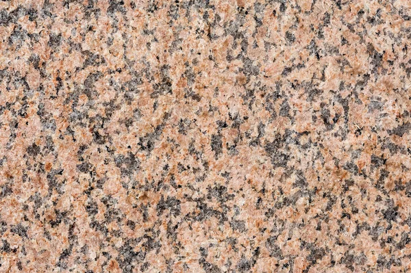 The natural pattern and texture of the red granite surface. Multicolored stone background.