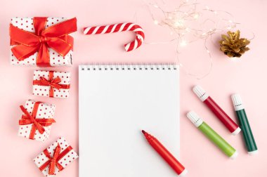 Noel arkaplanında keçeli kalemlerle dolu pembe bir masanın üzerine yazılmış bir dilek listesi. Noel konsepti, yeni yıl, planlar ve dilekler