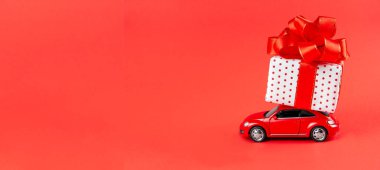 Moskova, Rusya, 14 Ocak 2021. Bayrak kırmızısı retro araba, 8 Mart Sevgililer Günü, 14 Şubat, Noel, Yeni Yıl bayramları için teslimat yapıyor. Kırmızı arka planda hediyeli oyuncak araba..