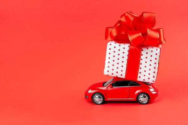 Moskova, Rusya, 14 Ocak 2021. Kırmızı retro araba 8 Mart, Sevgililer Günü, 14 Şubat, Noel, Yeni Yıl için teslimat yapıyor. Kırmızı arka planda hediyeli oyuncak araba..