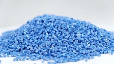 Polipropilenden yapılmış ikincil granül, Mavi Plastik topaklar masaya dökülüyor. Sanayi için granüllerdeki plastik hammaddeler. Polimer reçine. Çiğ plastik geri dönüşüm kavramı