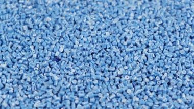 Polipropilenden yapılmış ikincil granül, masaya düşen mavi plastik topaklar. Sanayi için granüllerdeki plastik hammaddeler. Polimer reçine. Çiğ plastik geri dönüşüm kavramı
