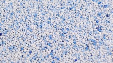 Polipropilenden yapılmış ikincil granül, açık mavi plastik topaklar masaya dökülüyor. Sanayi için granüllerdeki plastik hammaddeler. Polimer reçine. Çiğ plastik geri dönüşüm kavramı