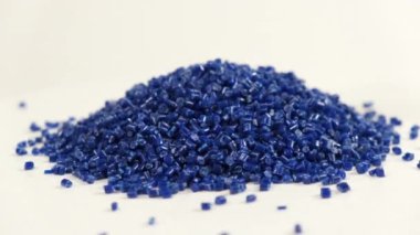 Polipropilenden yapılmış ikincil granül masaya dökülen koyu plastik topaklar. Sanayi için granüllerdeki plastik hammaddeler. Polimer reçine. Çiğ plastik geri dönüşüm kavramı