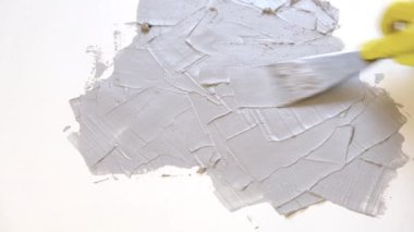 Lastik sarısı eldivendeki bir el bir spatula tutar ve tahtaya macun sürer. Yenileme, raf, yaratıcılık ve tasarım konsepti.