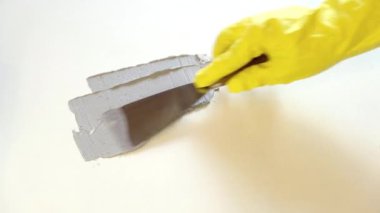 Lastik sarısı eldivendeki bir el bir spatula tutar ve tahtaya macun sürer. Yenileme, raf, yaratıcılık ve tasarım konsepti.