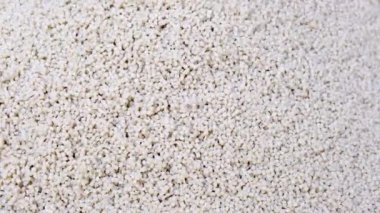 Polipropilenden yapılmış ikincil granül, beyaz plastik topaklar. Sanayi için granüllerdeki plastik hammaddeler. Polimer reçine. Çiğ plastik geri dönüşüm kavramı.