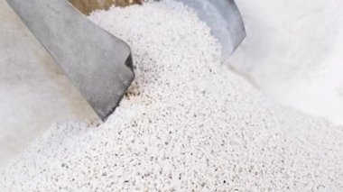 Beyaz ikincil işleme plastik granülü granülatörden küçük taneciklere ayrılır. Plastik geri dönüşüm kavramı, ikincil hammadde üretimi. Beyaz plastik topaklar ufalanır.