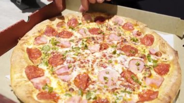 Sokakta pizza götüren bir elin yakınına. Medya. Paketteki bbq pizzasından dilime doğru hareket et. Fast food kavramı.