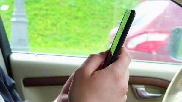 Mans mână ține telefonul și atinge ecranul cu degetele într-o mașină. Folosirea telefonului în timp ce conduceți, plata pentru parcare, apelarea la asistență tehnică. Rusia, Moscova, 05.20.2021 — Videoclip de stoc