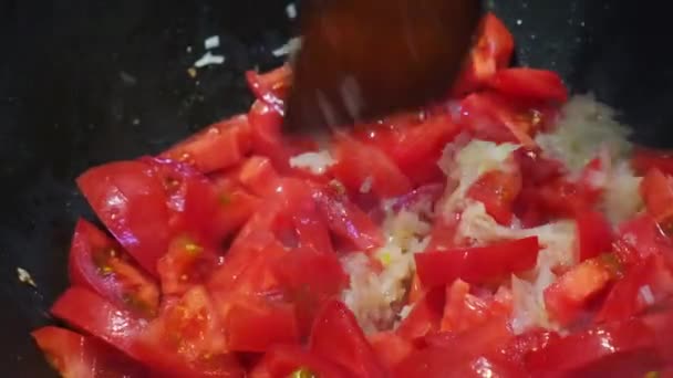 中華鍋で野菜を炒める.油でトマトや玉ねぎを鍋に揚げ、木製のへらと混合されます.料理のコンセプト、レシピ. — ストック動画