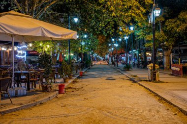Edirne, Türkiye - 5 Ekim 2020; Edirne Karaagac 'ta akşam saatleri. Şirin bir kafenin önünde. Arka planda ağaçlar olan sokak lambaları..