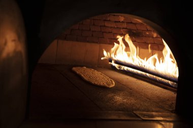 Türk mutfağı, taş tuğladan yapılmış pide ekmeği ahşap tahtada doğal alev fırını, taze pişmiş ekmek, fotokopi alanı. Fırın ya da fırın konsepti resmi.