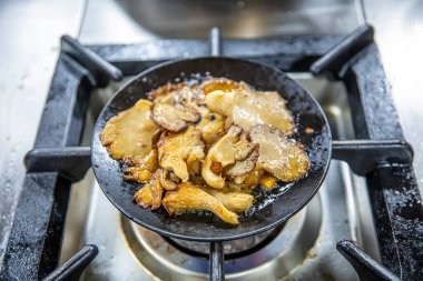 Kızarmış istiridye mantarı. Siyah dökme demir tavada taze bitkilerle kızartılmış mantar. Üst görünüm