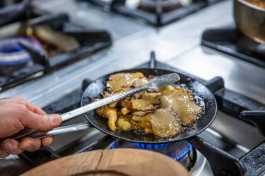 Kızarmış istiridye mantarı. Siyah dökme demir tavada taze bitkilerle kızartılmış mantar. Üst görünüm