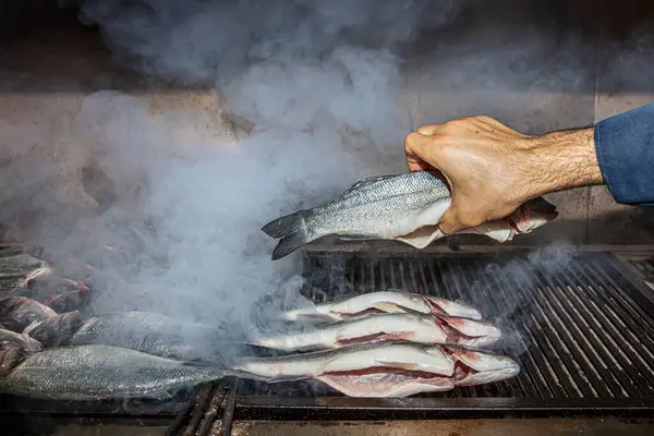 Grilled sea bass fish closeup. In process. European sea-bass, chef is grilling in the kitchen - BBQ — Stock Image Grilled Sea Bass Fish Closeup Process European Sea Bass Chef Royalty Free Stock Images