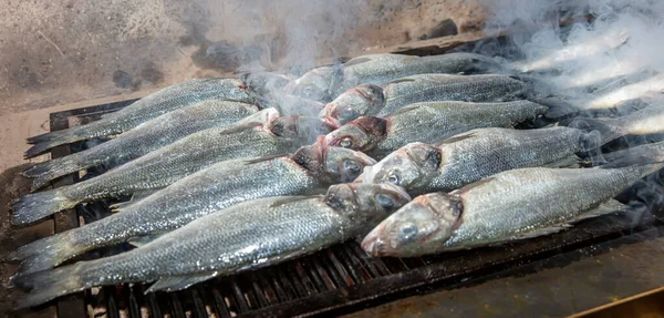 Grilled sea bass fish closeup. In process. European sea-bass, chef is grilling in the kitchen - BBQ — Stock Image Grilled Sea Bass Fish Closeup Process European Sea Bass Chef Royalty Free Stock Photos