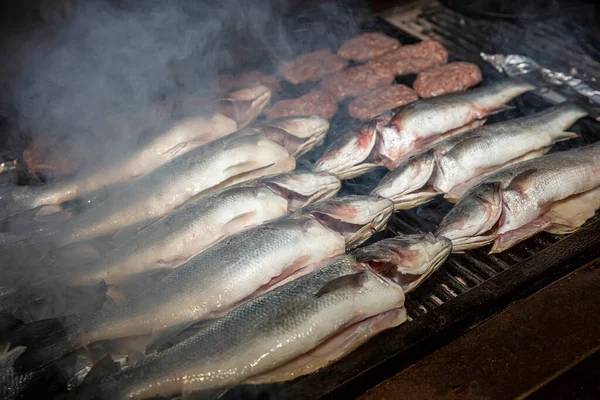 Grilled sea bass fish closeup. In process. European sea-bass, chef is grilling in the kitchen - BBQ — Stock Image Grilled Sea Bass Fish Closeup Process European Sea Bass Chef Royalty Free Stock Images