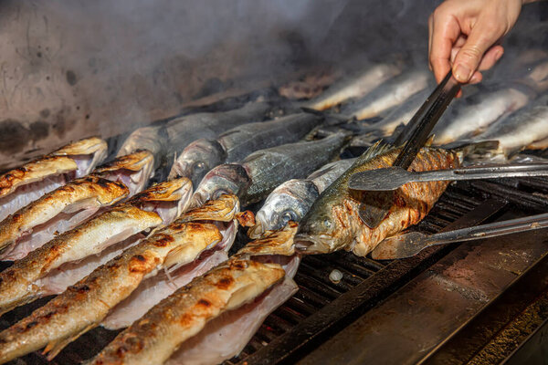 Grilled sea bass fish closeup. In process. European sea-bass, chef is grilling in the kitchen - BBQ