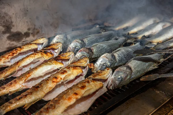 Grilled sea bass fish closeup. In process. European sea-bass, chef is grilling in the kitchen - BBQ