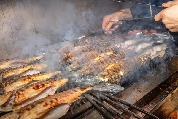 Grilled sea bass fish closeup. In process. European sea-bass, chef is grilling in the kitchen - BBQ — Stock Image Grilled Sea Bass Fish Closeup Process European Sea Bass Chef Stock Photo
