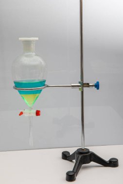 The study Separating by filtration the component substances from liquid mixture in Lab. Separating natural product use dichloromethane with water have two layer blue and yellow in separating funnel. clipart