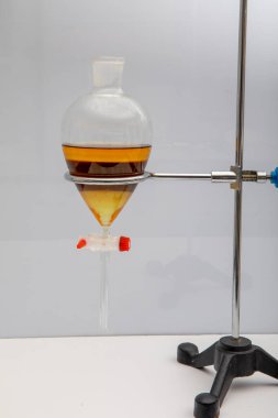 Laboratuvardaki sıvı karışımından bileşenleri filtreleme yoluyla ayıran çalışma. Doğal ürünleri birbirinden ayıran diklorometan ile suyu birbirinden ayıran bacanın iki katmanı mavi ve sarıdır..