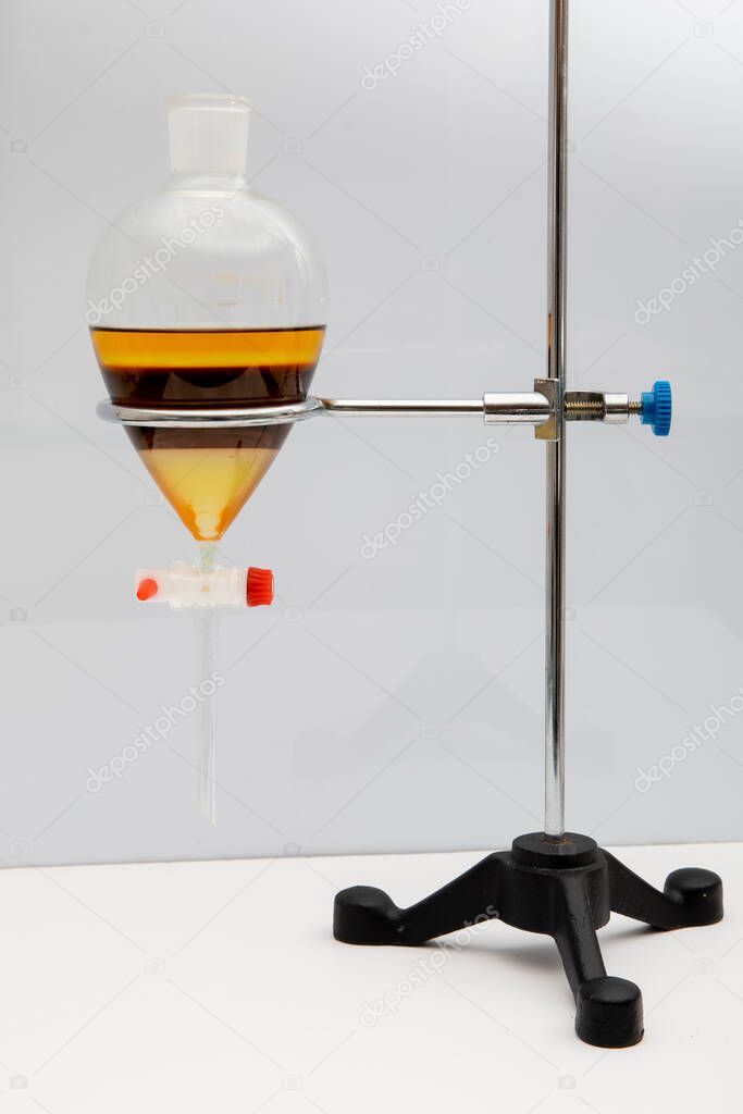 The study Separating by filtration the component substances from liquid mixture in Lab. Separating natural product use dichloromethane with water have two layer blue and yellow in separating funnel.