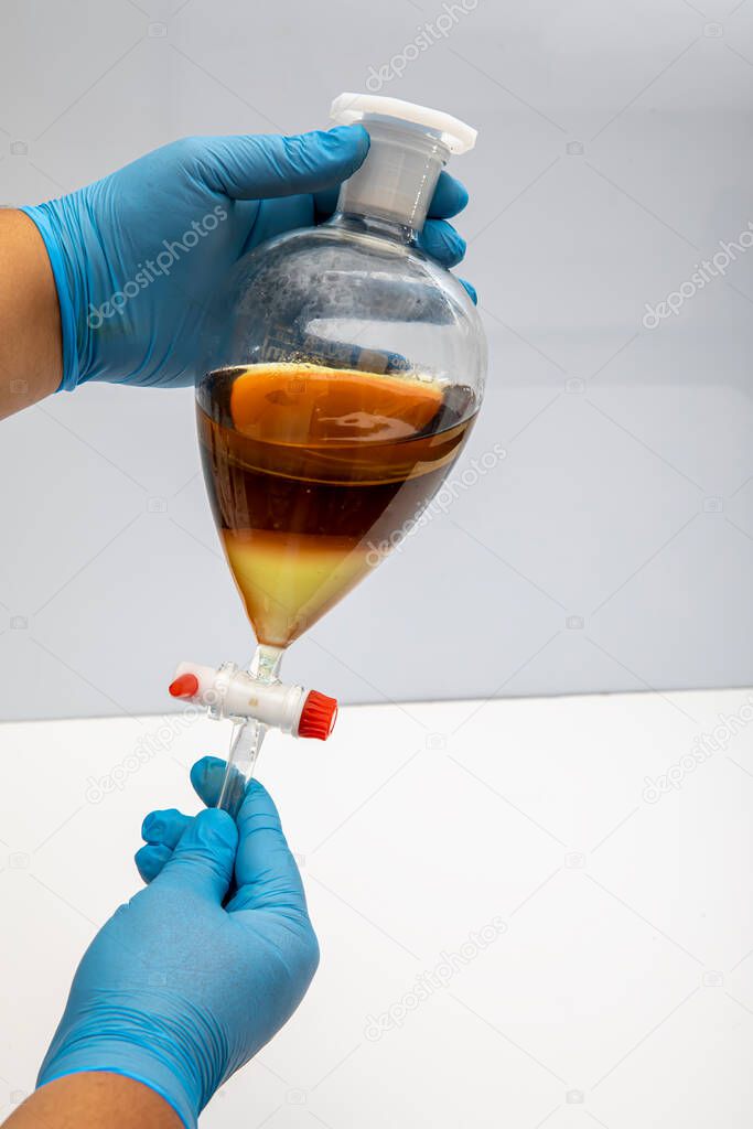 The study Separating by filtration the component substances from liquid mixture in Lab. Separating natural product use dichloromethane with water have two layer blue and yellow in separating funnel.