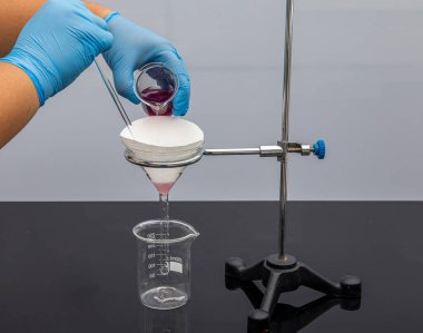 Laboratuvarda filtre kağıdı. Bilimadamları cam hunideki filtre kağıdından filtreleyerek kimyasal filtreleme yapıyorlar. Laboratuvarda eczacı filtreleme maddesi var..