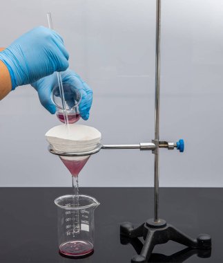 Laboratuvarda filtre kağıdı. Bilimadamları cam hunideki filtre kağıdından filtreleyerek kimyasal filtreleme yapıyorlar. Laboratuvarda eczacı filtreleme maddesi var..