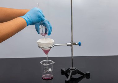 Laboratuvarda filtre kağıdı. Bilimadamları cam hunideki filtre kağıdından filtreleyerek kimyasal filtreleme yapıyorlar. Laboratuvarda eczacı filtreleme maddesi var..