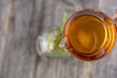 Kaba ahşap arka planda, adaçayı ve bal tazeleyici. Seçili odak. Nane yaprakları, kaşıklı bal ve bir fincan sıcak çay. Bitkisellik ve modern eczacılık kavramı.