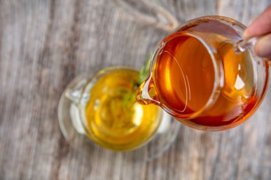 Kaba ahşap arka planda, adaçayı ve bal tazeleyici. Seçili odak. Nane yaprakları, kaşıklı bal ve bir fincan sıcak çay. Bitkisellik ve modern eczacılık kavramı.