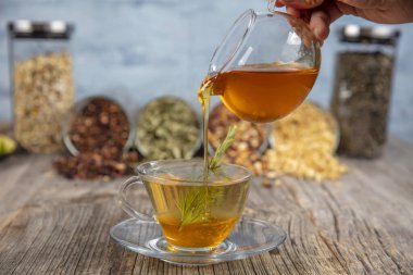 Kaba ahşap arka planda, adaçayı ve bal tazeleyici. Seçili odak. Nane yaprakları, kaşıklı bal ve bir fincan sıcak çay. Bitkisellik ve modern eczacılık kavramı.