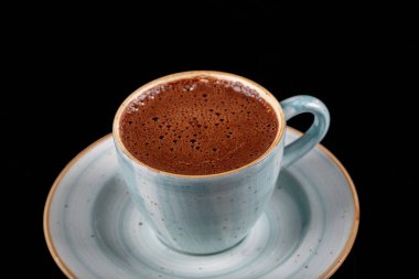 Siyah zemin üzerinde mavi porselen fincanda Türk kahvesi.