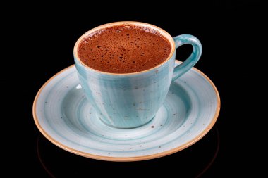 Siyah zemin üzerinde mavi porselen fincanda Türk kahvesi.