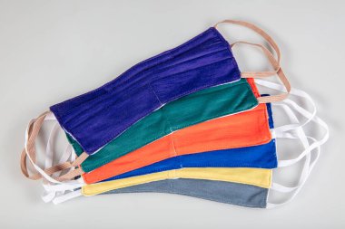 Üç tane elastik kulak halkalı yüz maskesi, üst üste yığılmış beyaz maske, arka planda mavi ve siyah. Coronavirus covid-19 salgını sırasında yeniden kullanılabilir pamuk kumaş maskeleri çok talep görüyor..