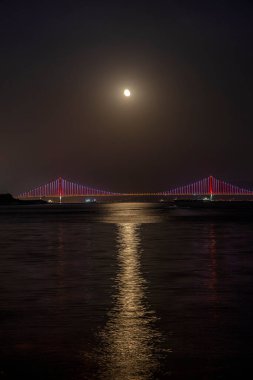 Osmangazi Köprüsü (İzmit Körfezi Köprüsü) ve dolunay. İzmit, Kokael, Turkey. Hepsi bu. Türkiye 'nin en uzun köprüsü ve dünyanın en uzun dördüncü asma köprüsü, merkez açıklığının uzunluğuyla.