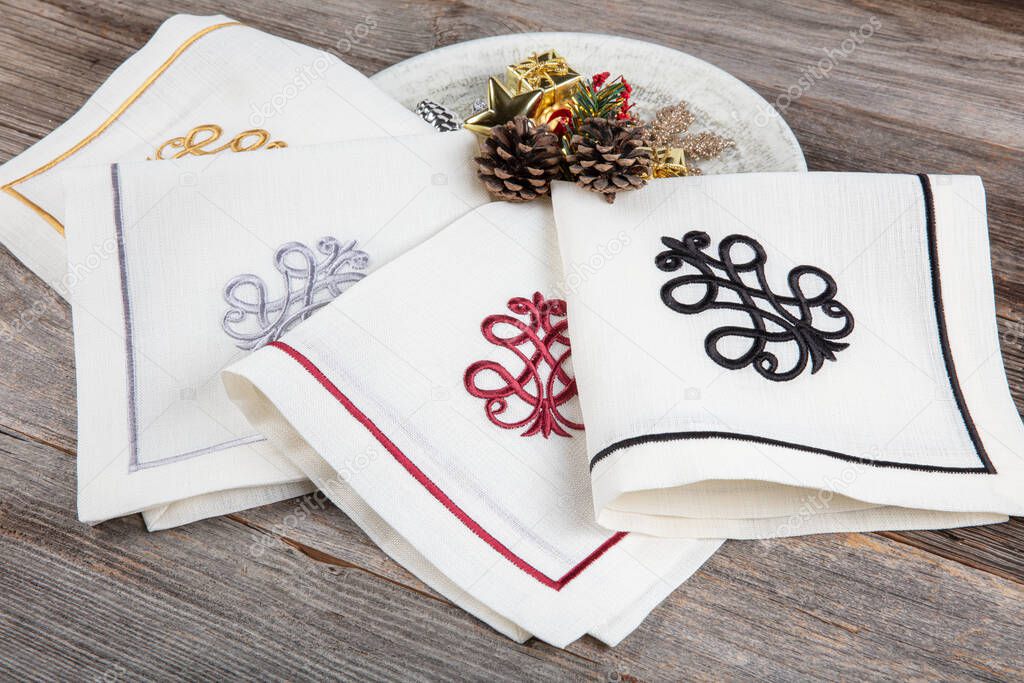 folded linen napkins on wooden table. luxury napkins with embroidery on the hem.