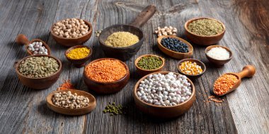 Vegan protein source.Various assortment of legumes, lentils, chickpea and beans assortment in different bowls on wooden table. Top view.
