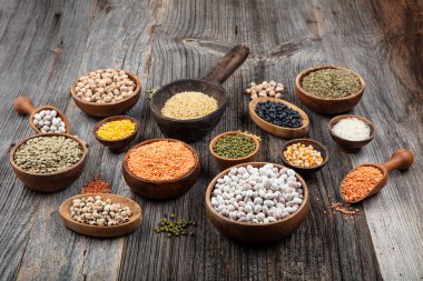 Vegan protein source.Various assortment of legumes, lentils, chickpea and beans assortment in different bowls on wooden table. Top view.