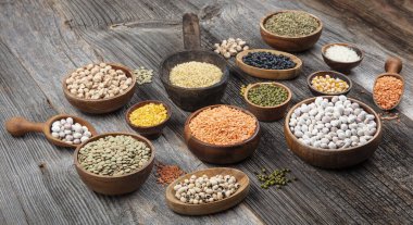 Vegan protein source.Various assortment of legumes, lentils, chickpea and beans assortment in different bowls on wooden table. Top view.
