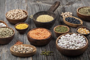 Vegan protein source.Various assortment of legumes, lentils, chickpea and beans assortment in different bowls on wooden table. Top view.
