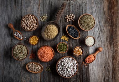 Vegan protein source.Various assortment of legumes, lentils, chickpea and beans assortment in different bowls on wooden table. Top view.