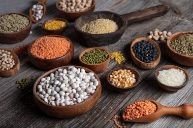 Vegan protein source.Various assortment of legumes, lentils, chickpea and beans assortment in different bowls on wooden table. Top view.