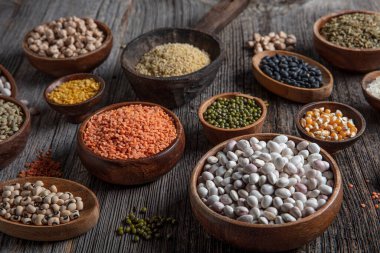 Vegan protein source.Various assortment of legumes, lentils, chickpea and beans assortment in different bowls on wooden table. Top view.